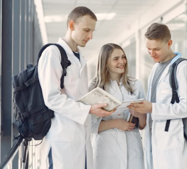 A group of healthcare students reviewing notes together in a clinical hallway